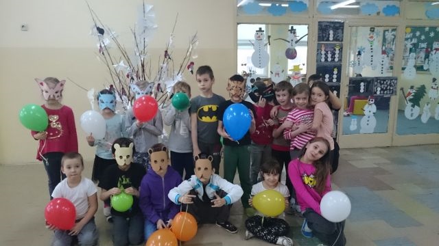 Zdjęcie przedstawiające dzieci podczas zabawy karnawałowej. Uczniowie trzymają w dłoniach kolorowe balony, niektórzy mają maski.