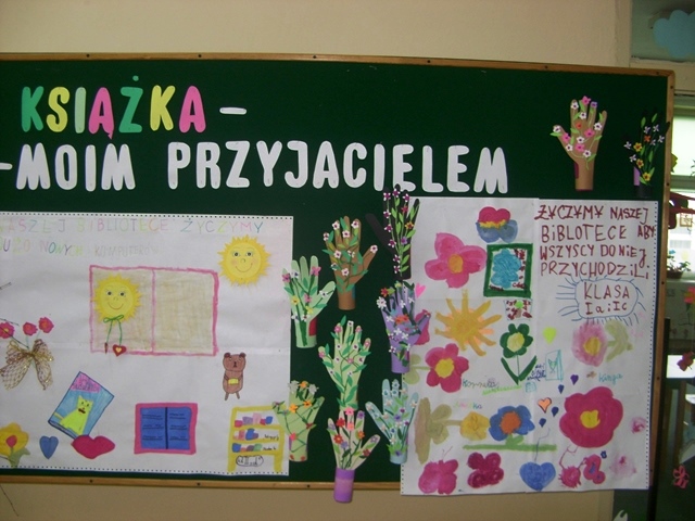 Zdjęcie przedstawia tablicę z kolorowymi plakatami zrobionymi przez dzieci. Powyżej widać napis “Książka - moim przyjacielem”.