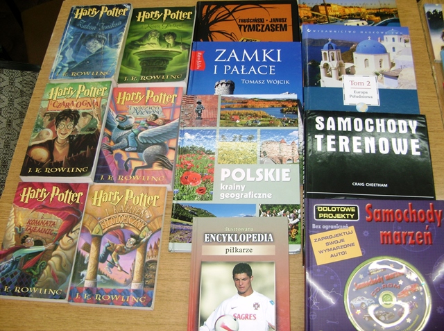 Zdjęcie wystawy książek. Na stole rozłożone m.in. książki z serii Harry Potter, "Encyklopedia piłkarze", "Samochody marzeń", "Polskie krainy geograficzne".