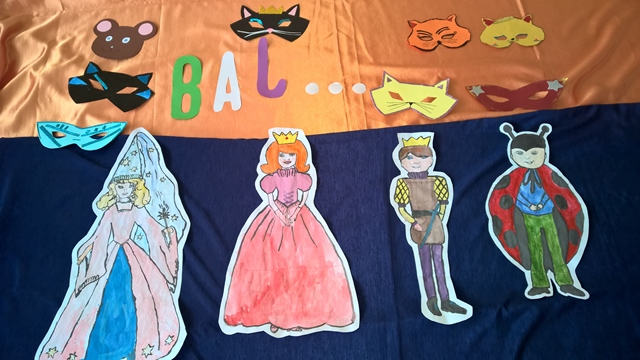 Dekoracja z napisem „Bal...”, karnawałowymi maskami i przebraniami.