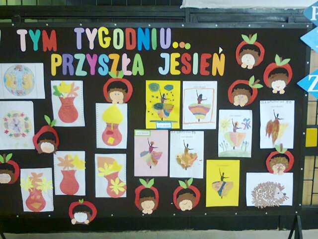 Tablica z napisem „W tym tygodniu... przyszła jesień” i jesiennymi rysunkami jeży oraz kolorowych liści w wazonach.