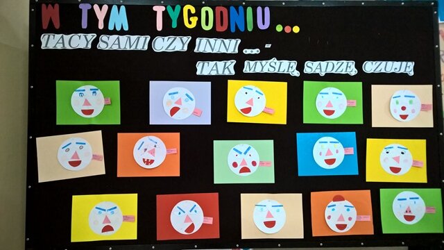 Dekoracyjna tablica z napisem „W tym tygodniu... Tacy sami czy inni... - tak myślę, sądzę, czuję”. Do tablicy przypięte są emotikonki przedstawiające różne emocje.