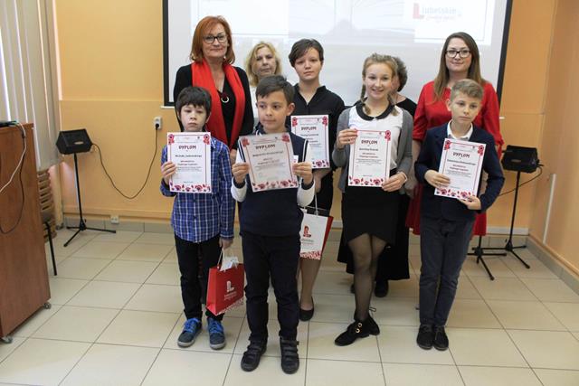 Zdjęcie przedstawiające uczniów i nauczycieli podczas wręczenia nagród za udział w konkursie. Dzieci prezentują dyplomy.