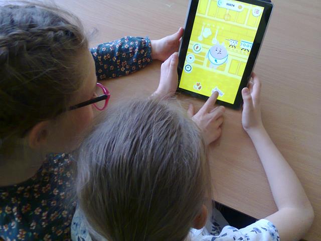 Zdjęcie dwóch uczennic korzystających z aplikacji edukacyjnej na tablecie.