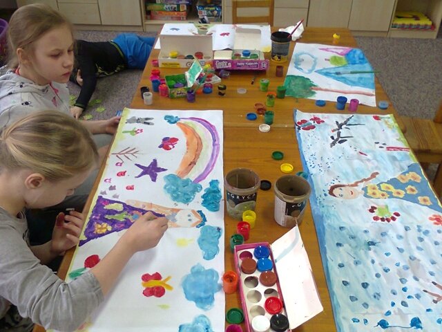 Zdjęcie przedstawiające uczennice podczas zajęć w świetlicy szkolnej. Dziewczęta malują obrazki farbami plakatowymi. 