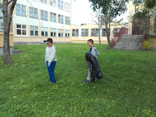 Zdjęcie przedstawia uczniów podczas prac porządkowych na terenie szkolnym.