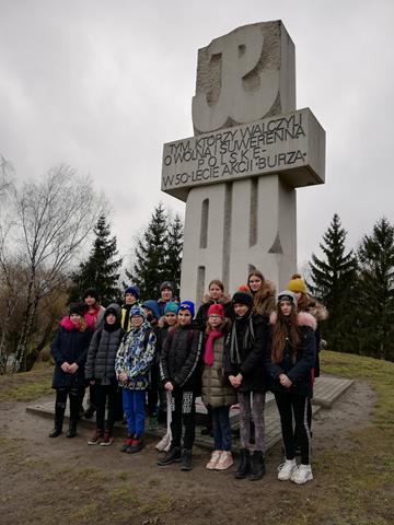 Zdjęcie uczniów na tle pomnika upamiętniającego tych, którzy walczyli o wolną i suwerenną Polskę – w 50-lecie akcji „Burza”.