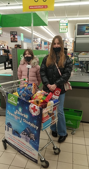 Zdjęcie prezentuje dwie uczennice w sklepie podczas zbiórki żywności dla potrzebujących.