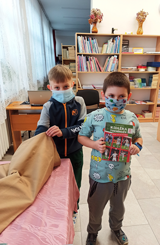 Zdjęcie, na którym jeden uczeń sięga do worka po książkę, a drugi stoi obok z wylosowaną już  książką.