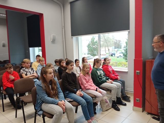 Zdjęcie przedstawia uczniów słuchających wykładu nauczyciela.