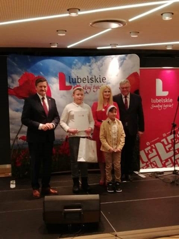 Zdjęcie przedstawia ucznia podczas odbioru nagrody za udział w konkursie.