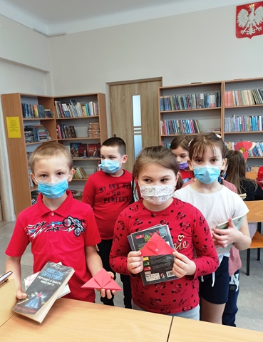 Dzieci w bibliotece z książkami w rękach.