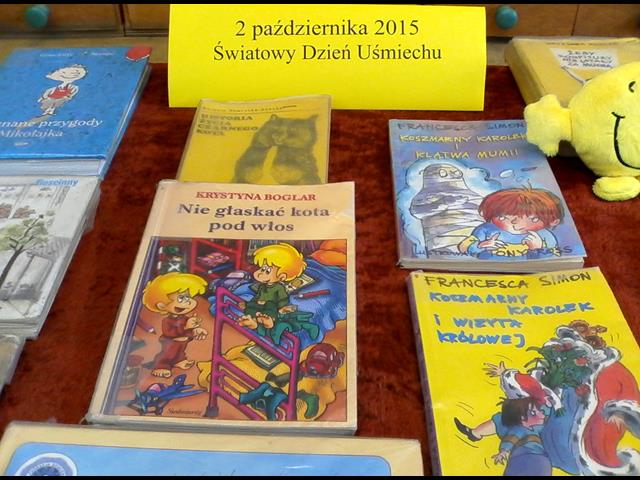 Rozłożone książki, których treść zmusza do śmiechu. Wśród nich napis: „2 października 2015 Światowy Dzień Uśmiechu”.