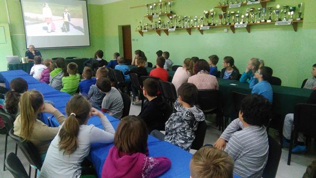 Zdjęcie przedstawia uczniów siedzących przy stołach w sali konferencyjnej podczas spotkania z funkcjonariuszem policji.