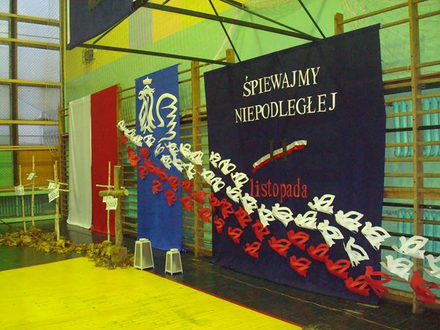 Zdjęcie przedstawia dekorację sali gimnastycznej z okazji uroczystości ,,Śpiewajmy Niepodległej’’.