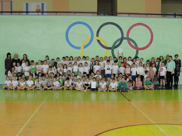 Zdjęcie prezentujące uczniów i nauczycielki w sali gimnastycznej po skończonych zawodach sportowych.