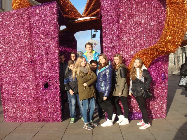 Grupa uczniów podczas wycieczki szkolnej. Dziewczęta i chłopcy stoją przy dekoracji świątecznej.