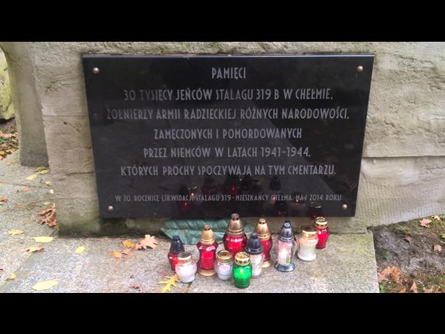Tablica upamiętniająca żołnierzy - jeńców Stalagu 319, przy której stoją zapalone znicze.