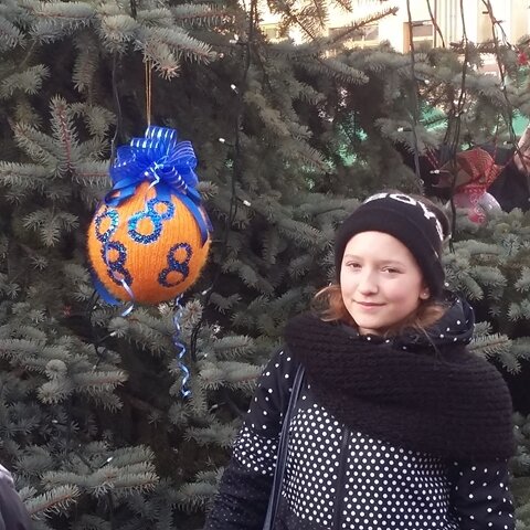 Uczennica stojącą przy ogromnej choince i zawieszonej bombki z logo „Ósemki”.