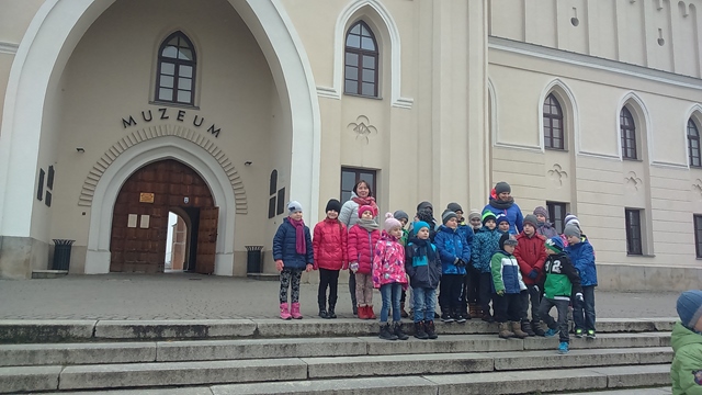 Zdjęcie przedstawia grupę uczniów z dwiema nauczycielkami podczas wycieczki szkolnej. Wszyscy stoją na schodach przed budynkiem muzeum.