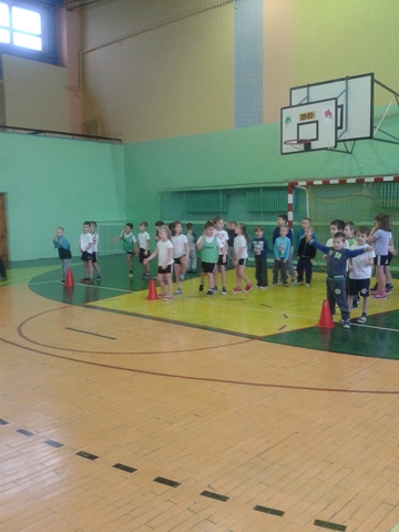 Uczniowie klas młodszych podczas zajęć sportowych w sali gimnastycznej.