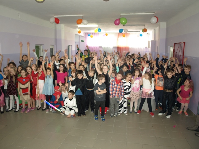 Zdjęcie przedstawia dużą grupę uczniów młodszych klas w trakcie zabawy karnawałowej