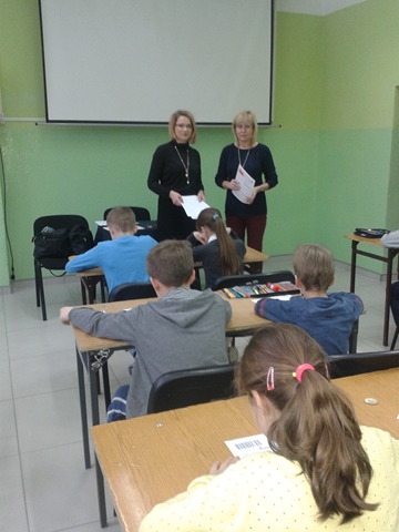 Zdjęcie prezentujące uczniów podczas konkursu. Przy tablicy stoją nauczycielki nadzorujące przebieg konkursu.