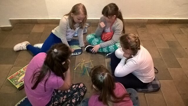 Uczniowie klasy IIIc na warsztatach „Dawne gry i zabawy” - kilka dziewczynek gra w bierki.