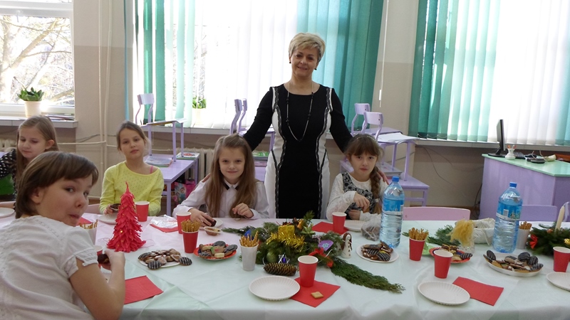 Zdjęcie przedstawiające uczennice z nauczycielką przy zastawionym stole podczas wigilii klasowej.