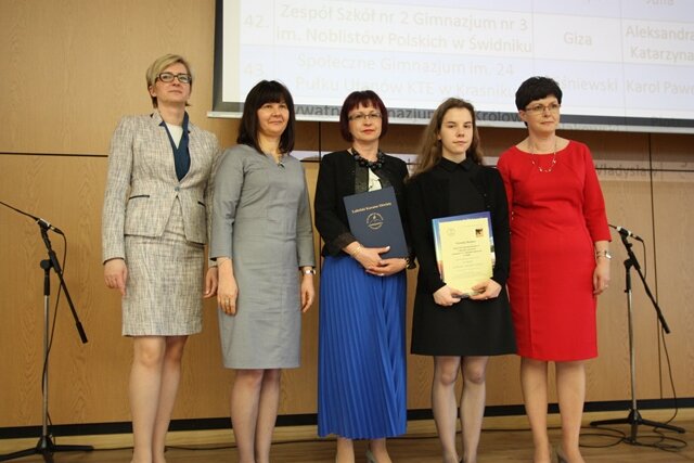 Zdjęcie przedstawia laureatkę konkursu, dyrekcję, nauczyciela oraz gości podczas uroczystej gali w Lublinie.