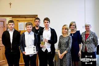 Trzyosobowa drużyna gimnazjalistów z opiekunką i organizatorami. Uczniowie prezentują dyplom i puchar.