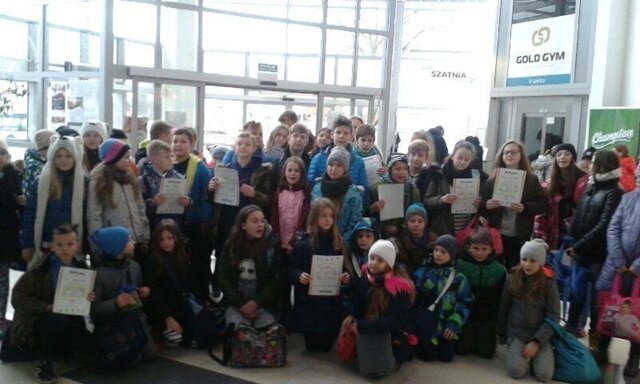 Grupa uczniów w aquaparku. Część uczniów prezentuje dyplomy.