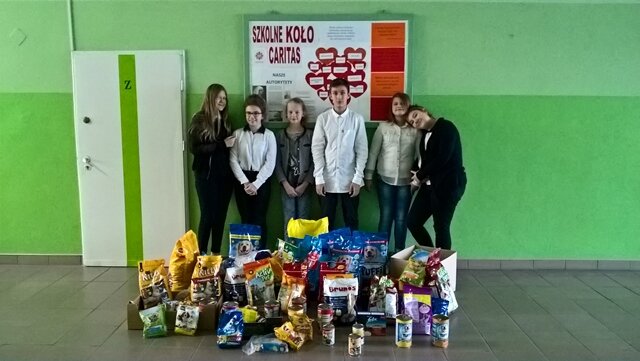 Grupa uczniów, a przed nimi zebrane opakowania karmy dla zwierząt.