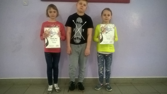 Zdjęcie przedstawia  troje uczniów podczas podsumowania konkursu. Laureaci prezentują otrzymane dyplomy.