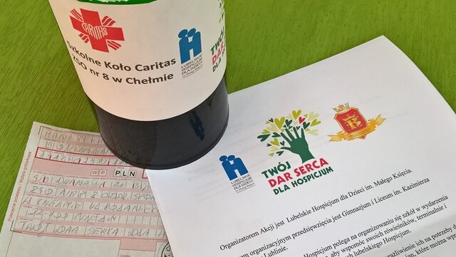 Zdjęcie puszki na datki pieniężne, przekazu pocztowego i karty z logo akcji „Twój DAR SERCA dla hospicjum”.