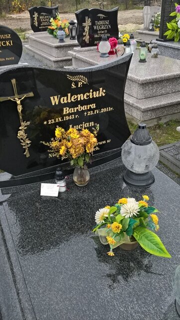 Zdjęcie nagrobka, na którym stoi znicz.