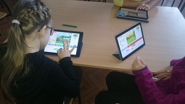 Zdjęcie uczennic z tabletami podczas zajęć z użyciem programu ScratchJr.