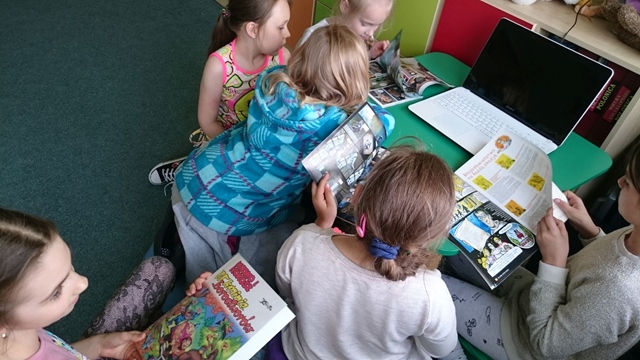 Uczniowie podczas zajęć w świetlicy szkolnej. Dzieci przeglądają komiksy. 