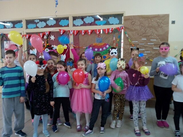 Zdjęcie przedstawiające uczniów podczas zabawy karnawałowej w świetlicy szkolnej. Dzieci trzymają w dłoniach kolorowe balony.