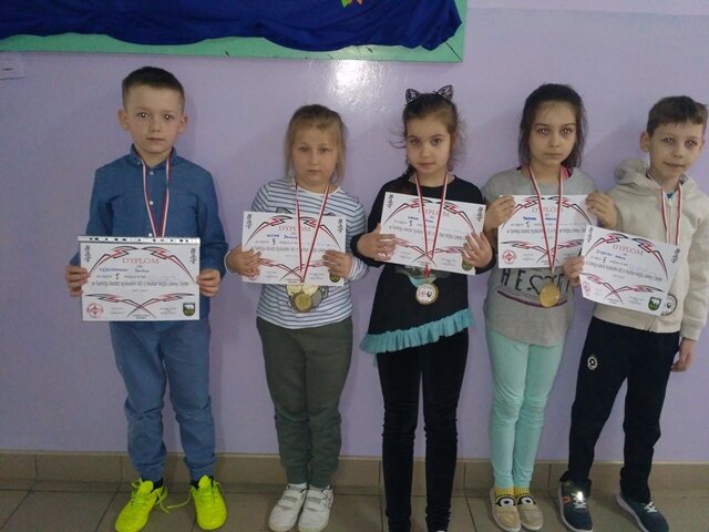 Trzy dziewczynki i dwóch chłopców z dyplomami i medalami.
