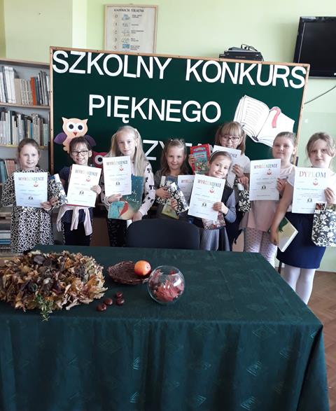 Laureaci Szkolnego Konkursu Pięknego Czytania dla klas I-III prezentujący dyplomy na tle okolicznościowej dekoracji.