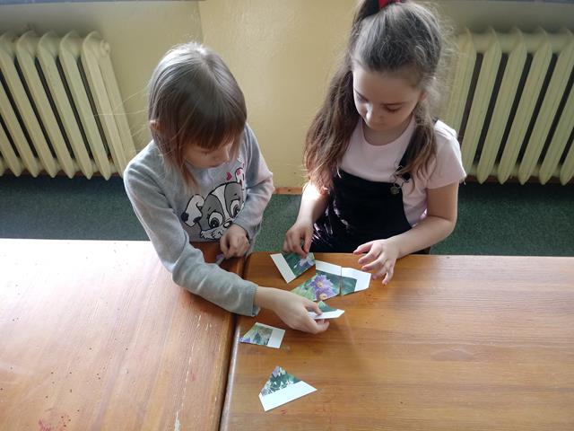  Dwie dziewczynki przy stoliku dopasowują do siebie elementy układanki.