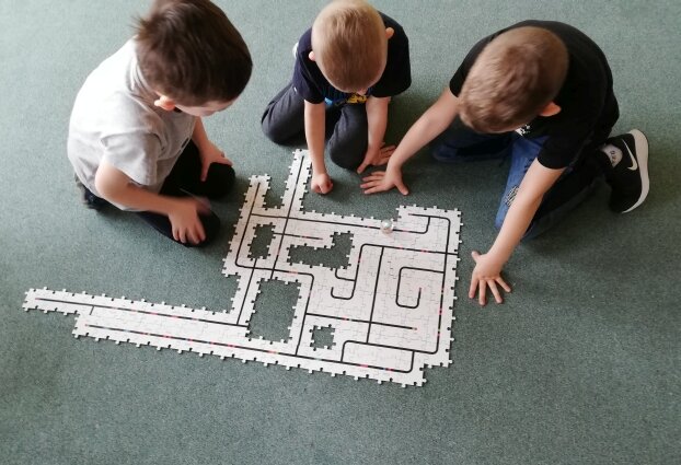 Uczniowie konstruujący tor z puzzli dla robota Ozobota.