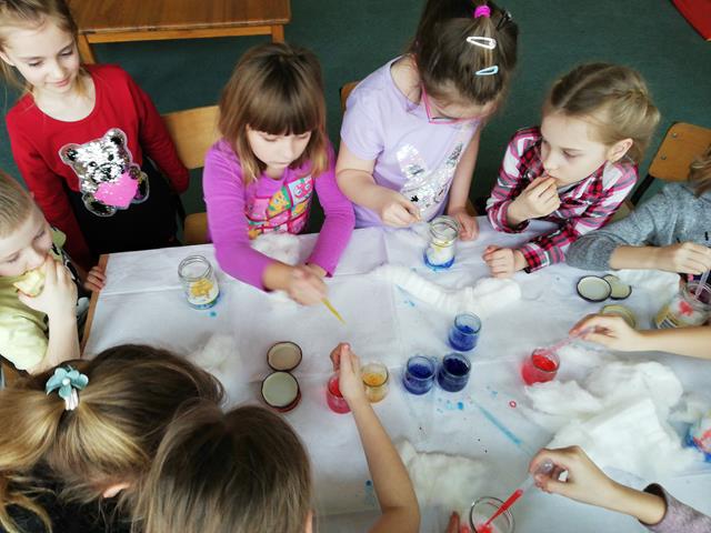 W świetlicy szkolnej uczniowie wykonują doświadczenie z wykorzystaniem kolorowych farb, waty i brokatu.