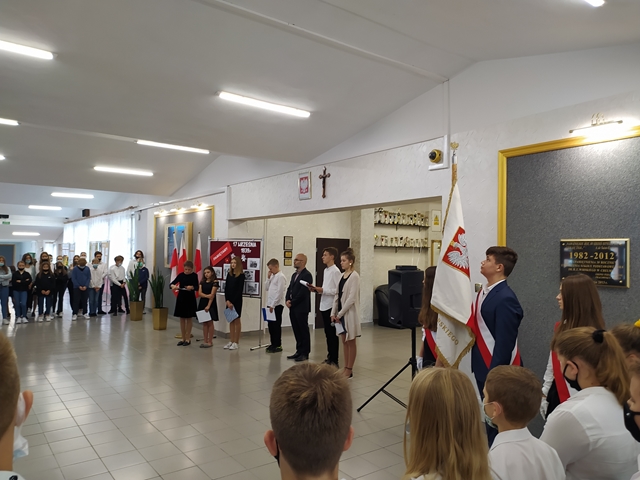 Na zdjęciu uczniowie stojący w holu szkoły podczas uroczystego apelu.