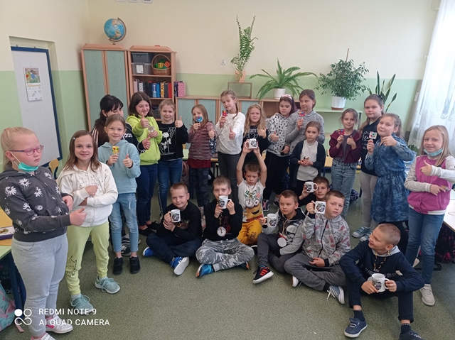 Zdjęcie grupowe uczniów klasy 3c świętujących Dzień Chłopaka. Chłopcy z dumą prezentują otrzymane w prezencie kubeczki ze swoimi imionami.
