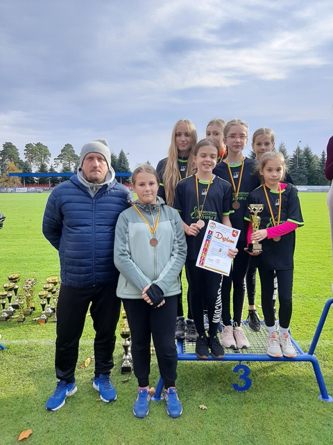 Trener z grupką uczennic nagrodzonych medalami i dyplomem za zajęcie III miejsca w biegach przełajowych.