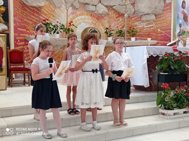 Zdjęcie na tle ołtarza przedstawia uczennice z młodszych klas podczas mszy świętej kończącej rok szkolny