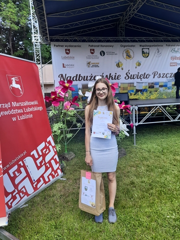 Zdjęcie przedstawiające uczennicę z dyplomem i nagrodą za udział w konkursie.