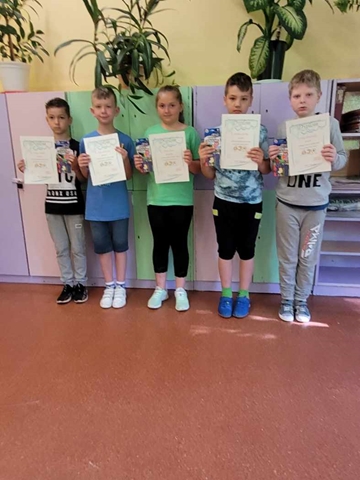 Zdjęcie przedstawiające pięcioro uczniów prezentujących dyplomy na tle szkolnych szafek.
